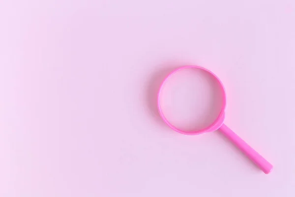 フラット パステル ピンク背景にバラの虫眼鏡を置く最小限の創造的な概念 — ストック写真