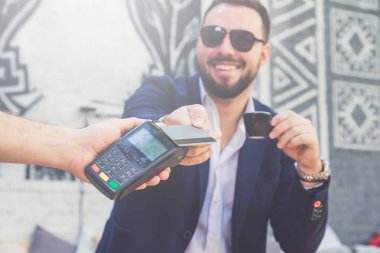 Kafede kredi kartı ile ödeme. Kahve arka planda tutan işadamı.