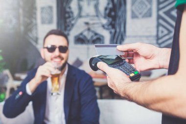 Kafede kredi kartı ile ödeme. Bardak bira arka planda tutan işadamı.