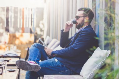 Kentsel guy içme kahve ve kafe açık havada onun tablet cihaz üzerinden müzik dinle.