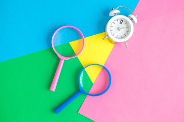 Gül ve mavi Büyüteç gözlük ile çalar saat düz renkli pastel çerçevede en az yaratıcı kavramı yatıyordu.