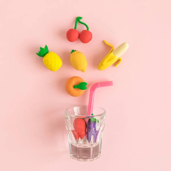 Flying fruits and glass with drinking straw abstract on rose.