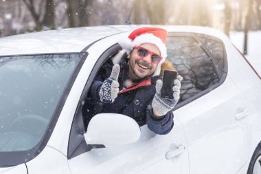 Santa şapka ve güneş gözlüğü olan boş ekran smartphone ve başparmak sürücü. Kış tatil ve seyahat kavramı.