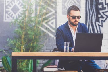 Kendine güvenen freelancer diz üstü kafede üzerinde çalışıyor. Kopya için alan.