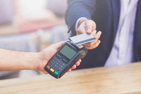 Close up of businessman paying with contactless credit card with nfc technology.