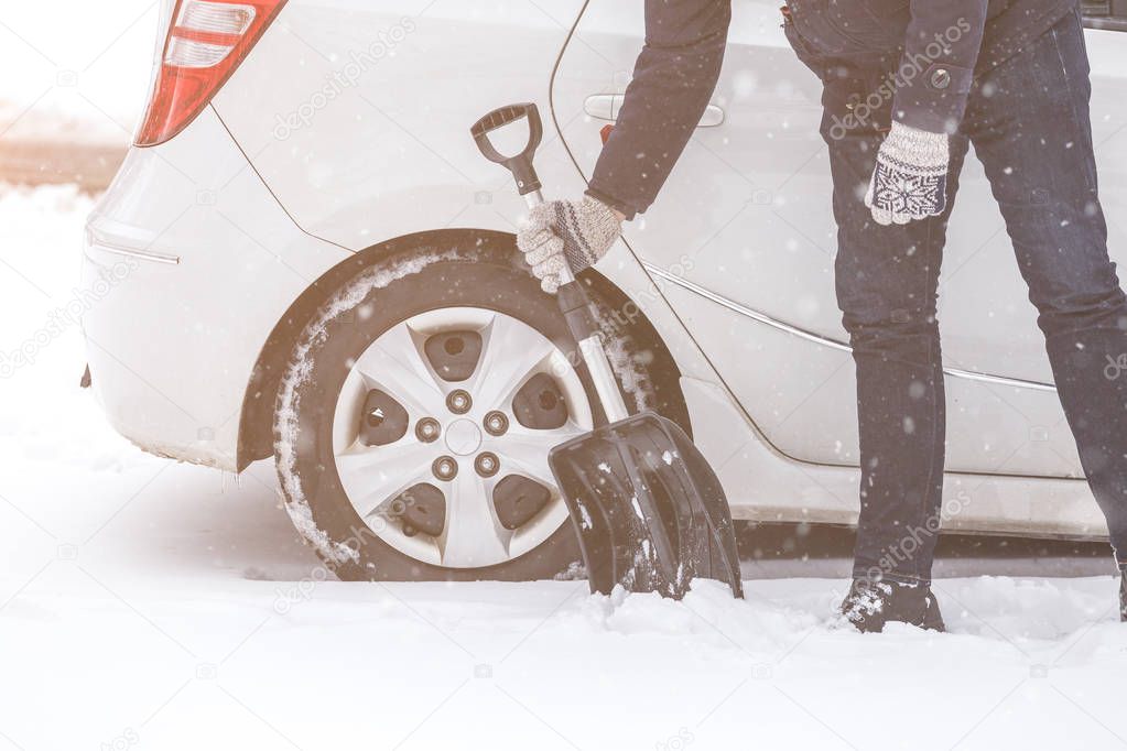Man holding shovel next to his car winter transportation concept.