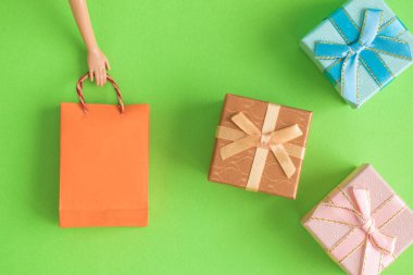 Kağıt alışveriş çantası ve hediye kutuları pastel yeşil arka plan en az yaratıcı kavramı üzerinde tutarak bebek el düz lay.