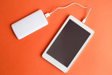Boş ekran dijital tablet cihazın güç Bankası turuncu arka plan en az yaratıcı kavramı ile şarj düz yatıyordu. Kopya için alan.