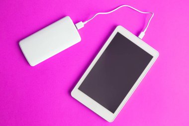 Boş ekran dijital tablet cihazın güç banka pembe arka plan en az yaratıcı kavramı ile şarj düz yatıyordu. Kopya için alan.