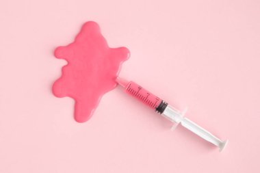 Şırınga ve leke pastel pembe arka plan en az yaratıcı kavramı karşı yüksek açılı görünüş.