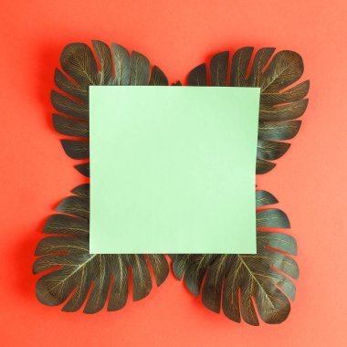 Monstera tropikal ile boş kağıt düz lay turuncu arka plan en az yaratıcı kavramı karşı bırakır. Kopya için alan.