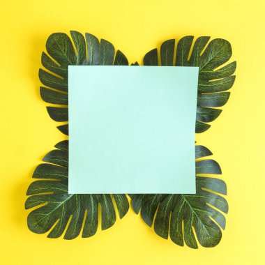 Monstera tropikal ile boş kağıt düz lay sarı arka plan en az yaratıcı kavramı karşı bırakır. Kopya için alan.