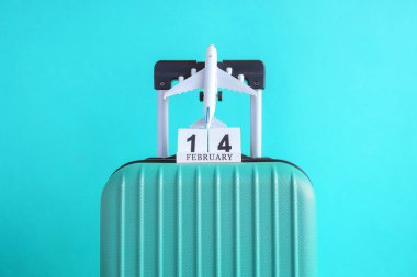 14 Şubat ahşap takvim ve uçak modeli oyuncak açık mavi renkli en az yaratıcı seyahat kavramı ile bavul.