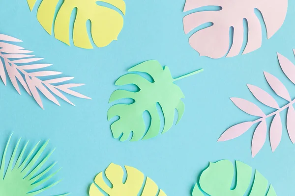 Bunte tropische Blätter aus Papier vor blauem Hintergrund minimales kreatives Muster. — Stockfoto