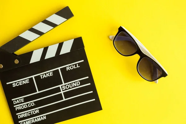 Flat lay of clapper board and glasses isolated on yellow.