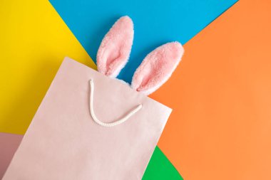 Çok renkli arka plan üzerinde alışveriş çantası tavşan kulakları üst görünümü soyut.