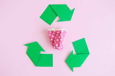 Flat lay of paper coffee cup and recycle symbol on rose. clipart