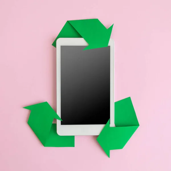 Flat lay of digital tablet device and recycling icon made of paper abstract. Blank screen, space for copy.