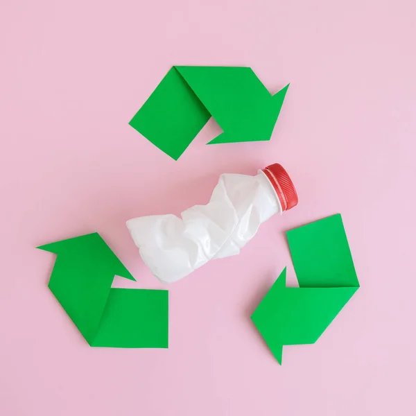 Colocação plana de garrafa de plástico com ícone de reciclagem feita de papel abstrato na rosa . — Fotografia de Stock