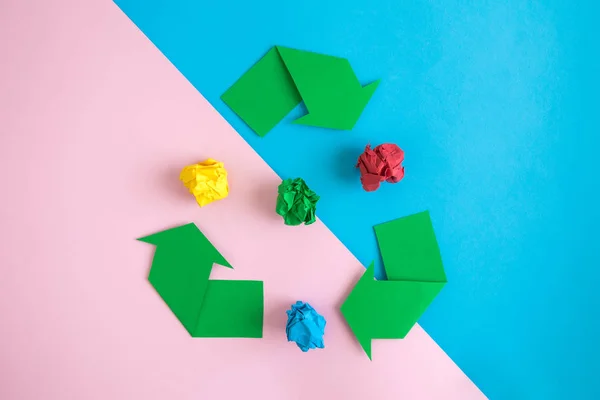 Flat lay of recycling sign with multicolored crushed paper abstract on pastel background.