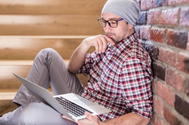 Moda freelancer ofis binasında merdivenlerde oturan ve dizüstü ekran bakarak.