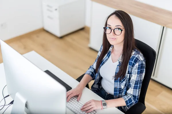 Mladá profesionálka pracující na projektu na svém stolním počítači v kanceláři. — Stock fotografie