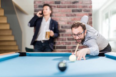 İki genç işadamı snooker oyunu oynuyor.