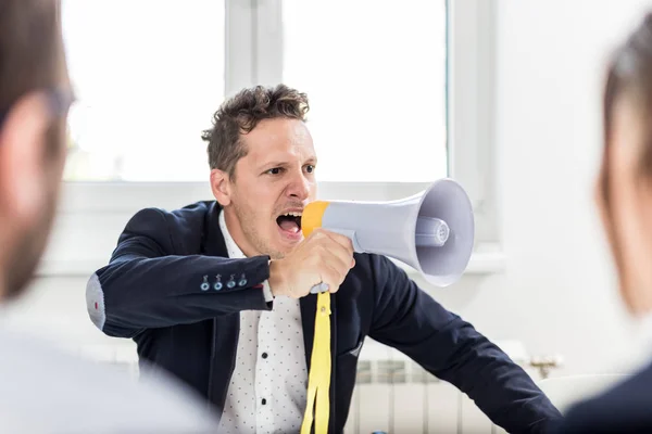 Young boss shouting at employees through megaphone in conference room. — 스톡 사진