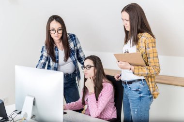 Masaüstü bilgisayar kullanarak proje üzerinde çalışan genç kız öğrenci grubu.