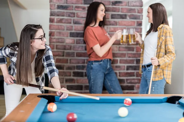 Neşeli kadın arkadaşlar bira zevk ve evde bilardo masası bilardo oyunu oynarken.