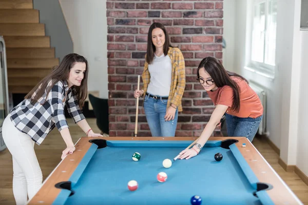 Evde bilardo masası bilardo oyunu oynayan neşeli kadın arkadaşlar.