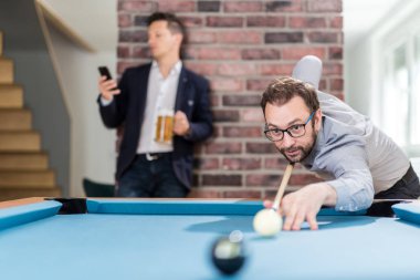İki genç işadamı snooker oyunu oynuyor.