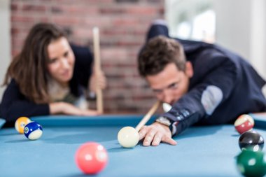 Young modern couple playing pool table billiard game.