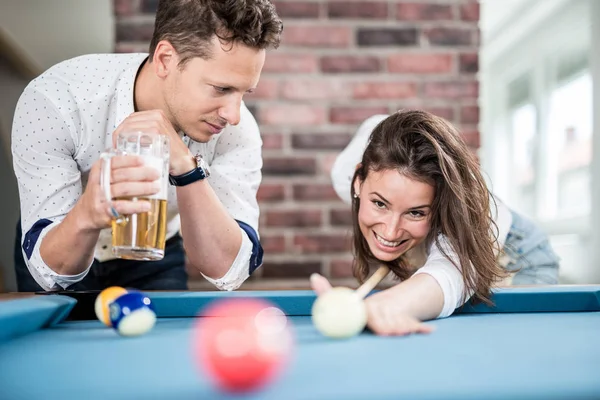 Beautiful fashionable couple playing pool table billiard game in office chill room.