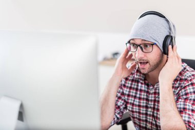 Bilgisayarında müzik dinleyen kulaklıklı yaratıcı adam.