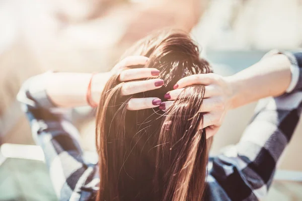 Back view of a brunette beauty coming through her wind swept hair with hands. — Stock Photo, Image