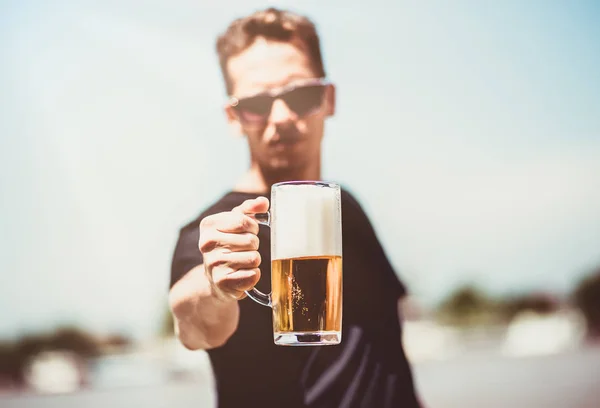 Close up de homem mostrando vidro cheio de cerveja . — Fotografia de Stock