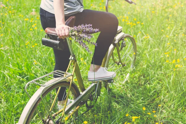 Nahaufnahme einer Frau auf einem Oldtimer-Fahrrad in der Natur. Sommer- oder Frühjahrskonzept. — Stockfoto