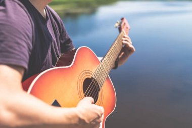 Doğada akustik gitar tutan adam elleri. Müzik ve yaz konseptleri.