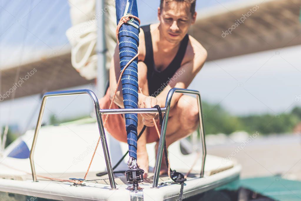 Sailing man standing on deck and preparing sailboat for the next trip.