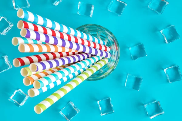 Flache Lage von Trinkhalmen in Glas und Eiswürfeln abstrakt isoliert auf blau. — Stockfoto