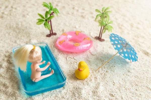 Menina boneca com brinquedos na praia de areia abstrata . — Fotografia de Stock