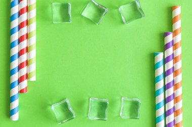 Yeşil izole içme pipetleri ve buz küpleri ile Yaratıcı yaz arka plan kompozisyon soyut. Kopyalama alanı.