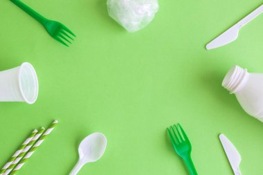 Plastik çatal bıçak içme pipetleri ve yeşil izole çanta yüksek açı görünümü. Gezegen kavramını kaydedin.