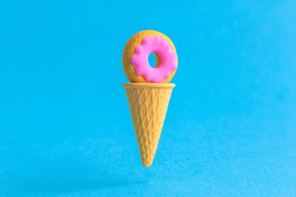 Конус мороженого с абстрактным пончиком изолирован на голубом . — стоковое фото