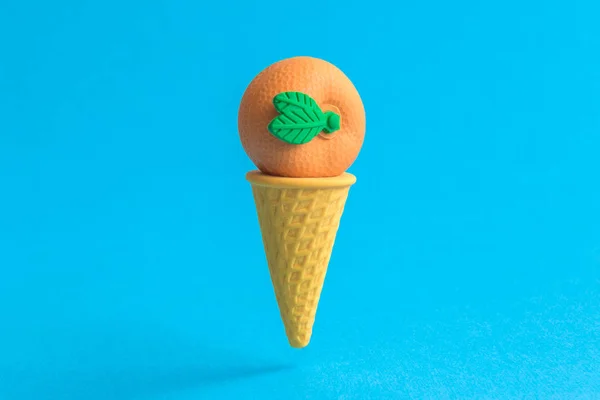 Orange in ice cream cone abstract isolated on blue.