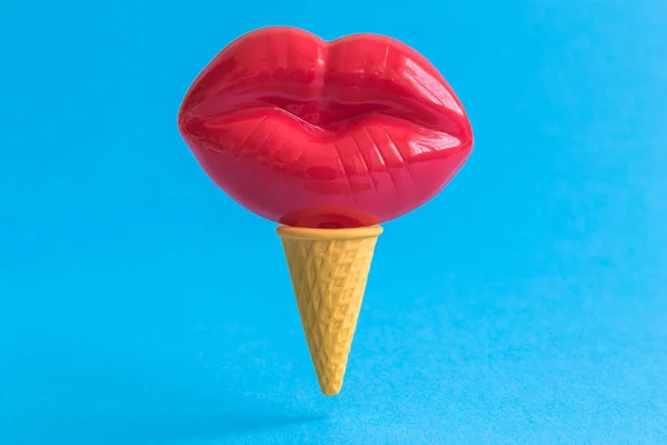 Female lips in ice cream cone abstract isolated on blue.