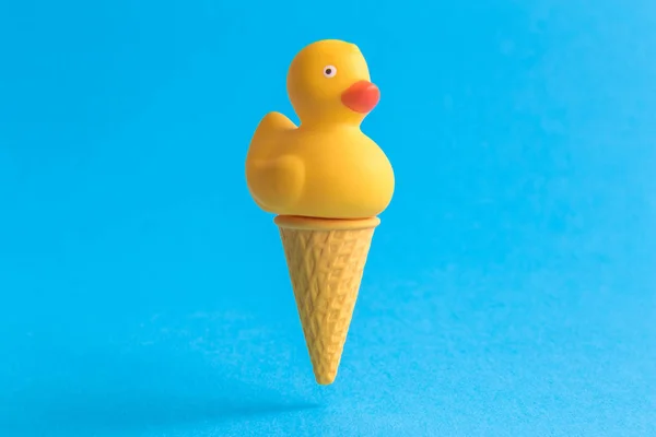 Pato de goma en cono de helado abstracto aislado en azul . — Foto de Stock