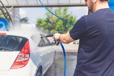 Adam araba yıkama açık havada basınçlı su ile arabasını yıkama.