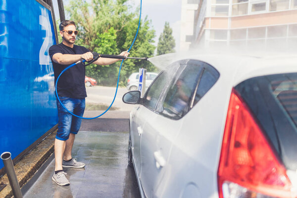 Close up of manual car wash with pressurized water in car wash.